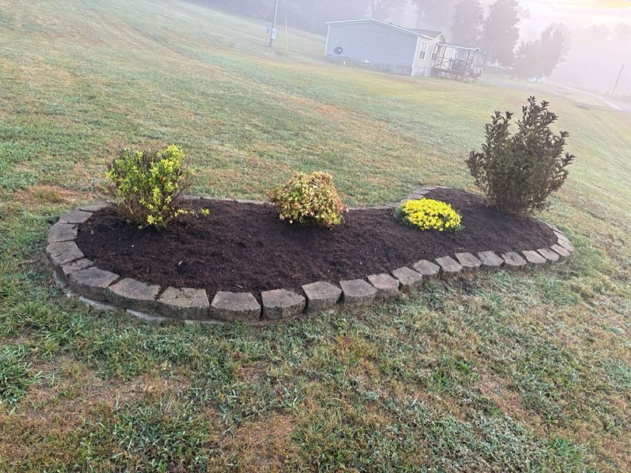 A stone-edged landscape island bed built by SEMO LawnCare & Landscaping